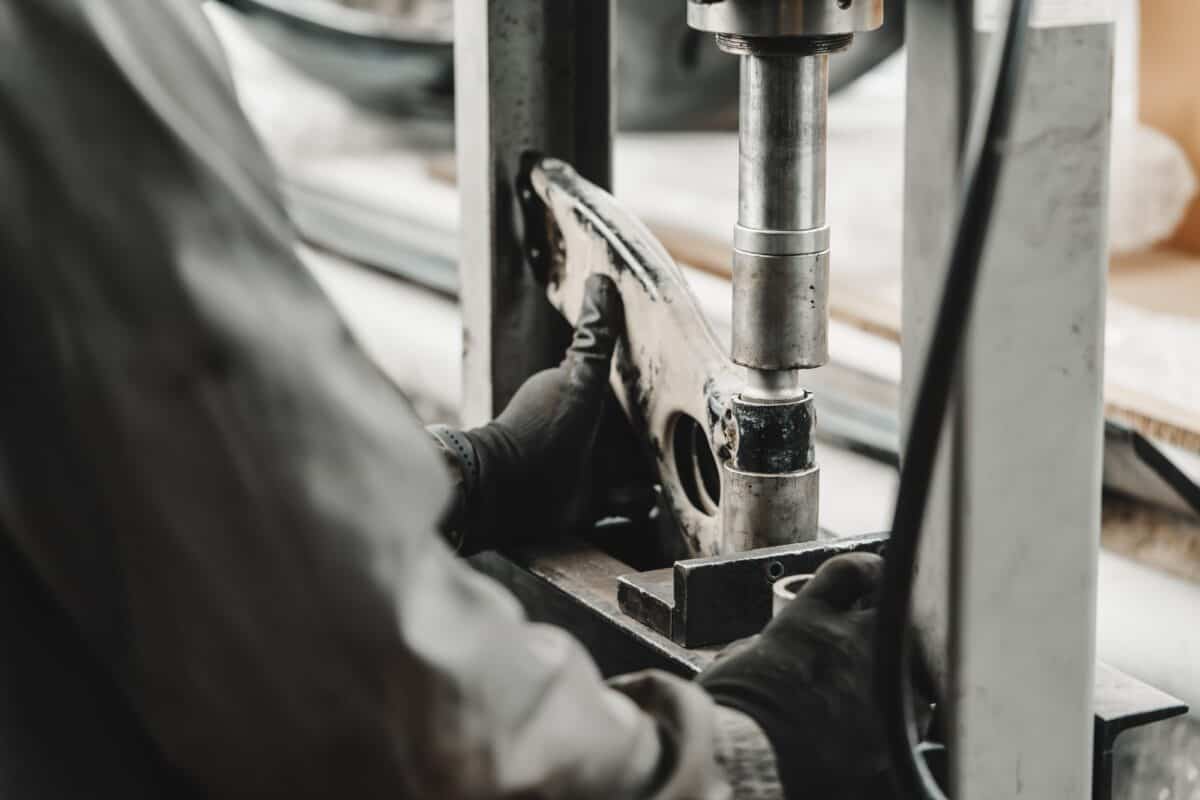 Gros plan d'un mécanicien automobile changeant le silent bloc dans la presse hydraulique du service automobile.