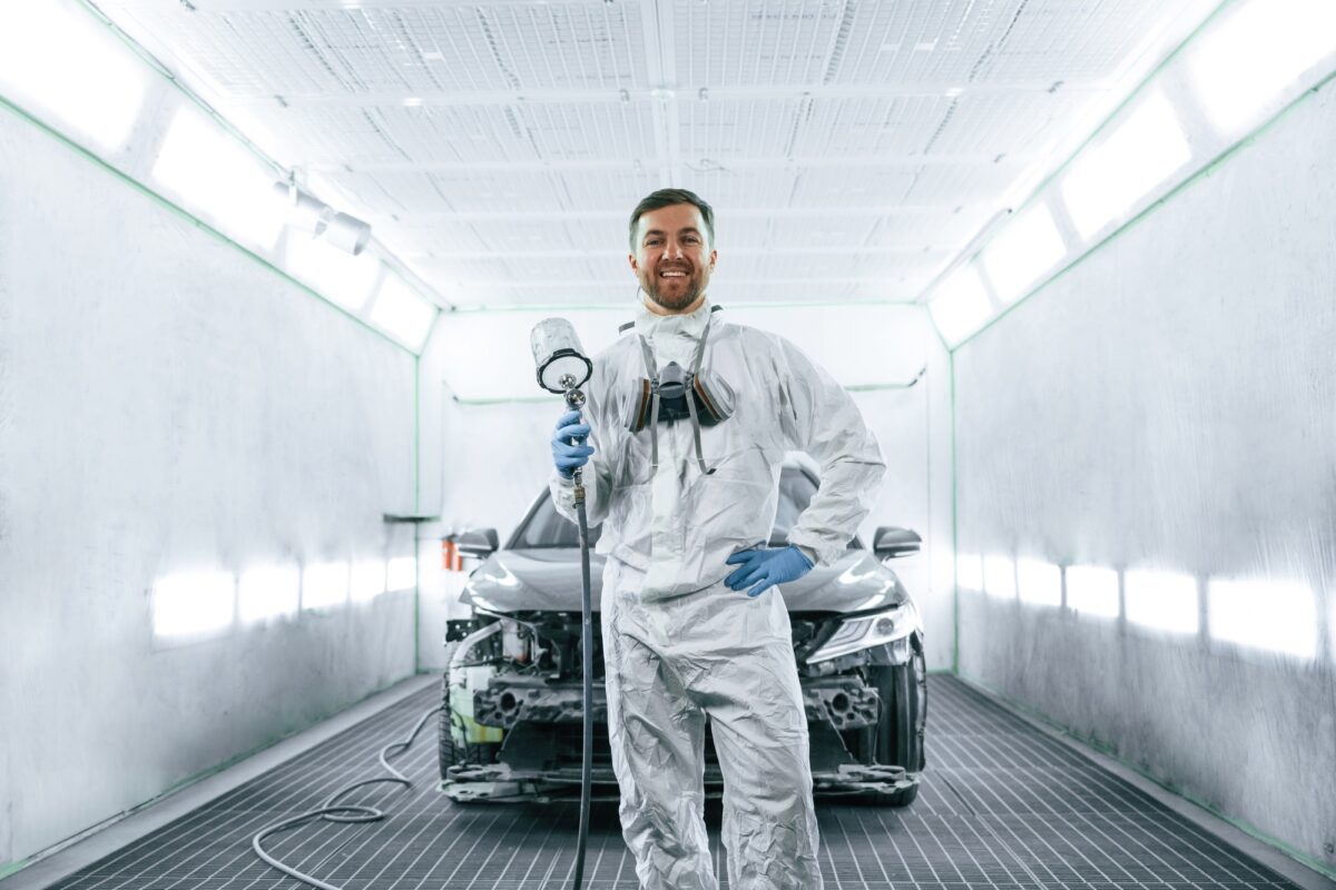 Éclairage artificiel lumineux. L'homme est debout et tient un pistolet à peinture pour automobile.