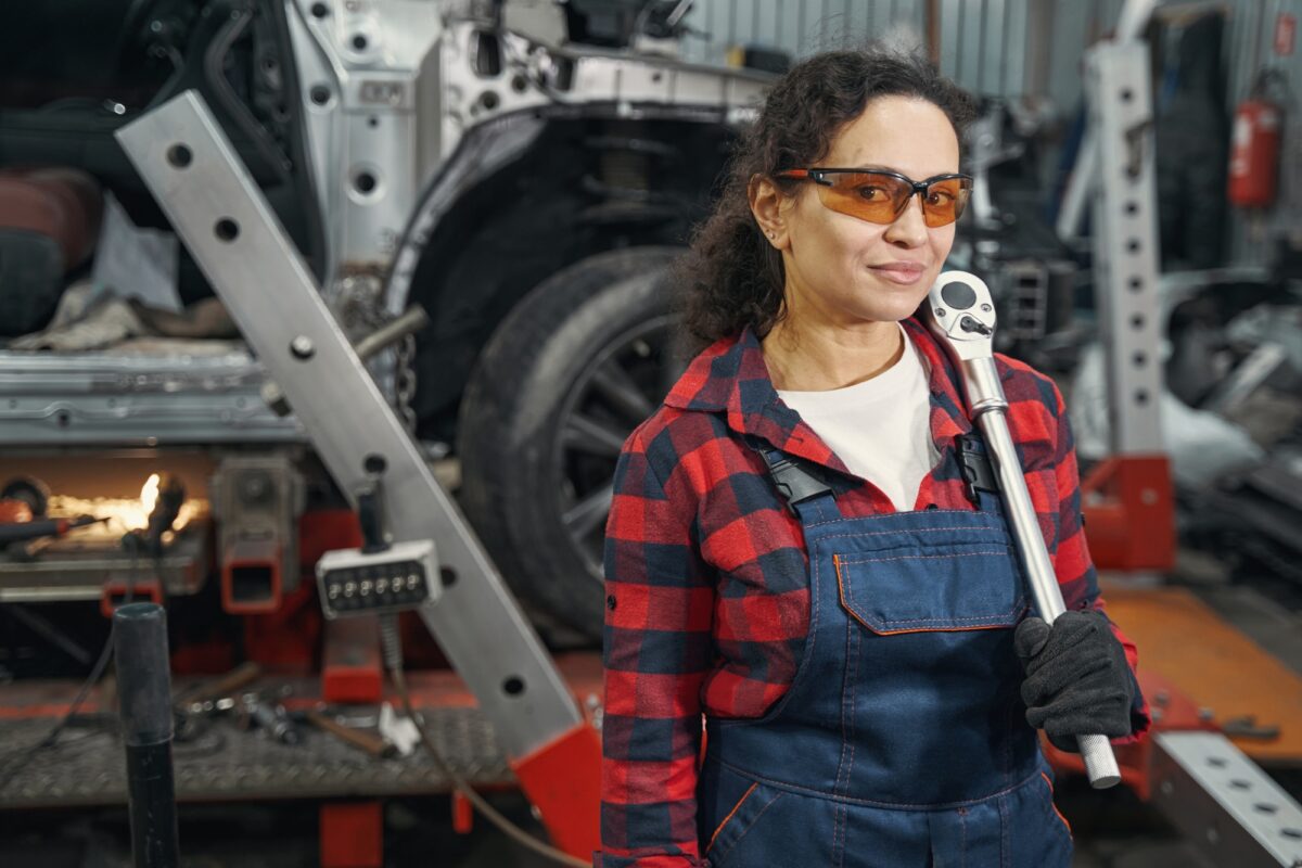 Femme mécanicien avec un outil de réparation de voiture dans un garage automobile