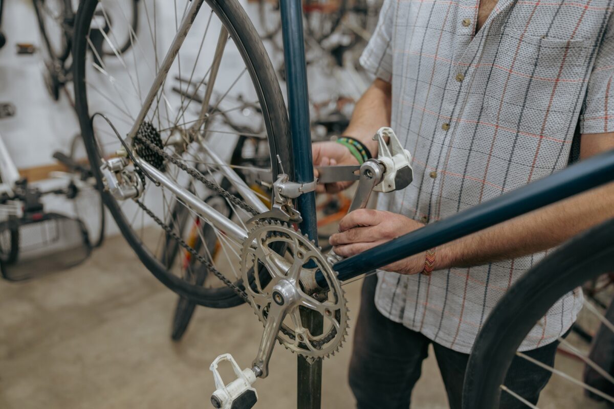 Close up of serviceman repairing modern bike using special tool while working in workshop