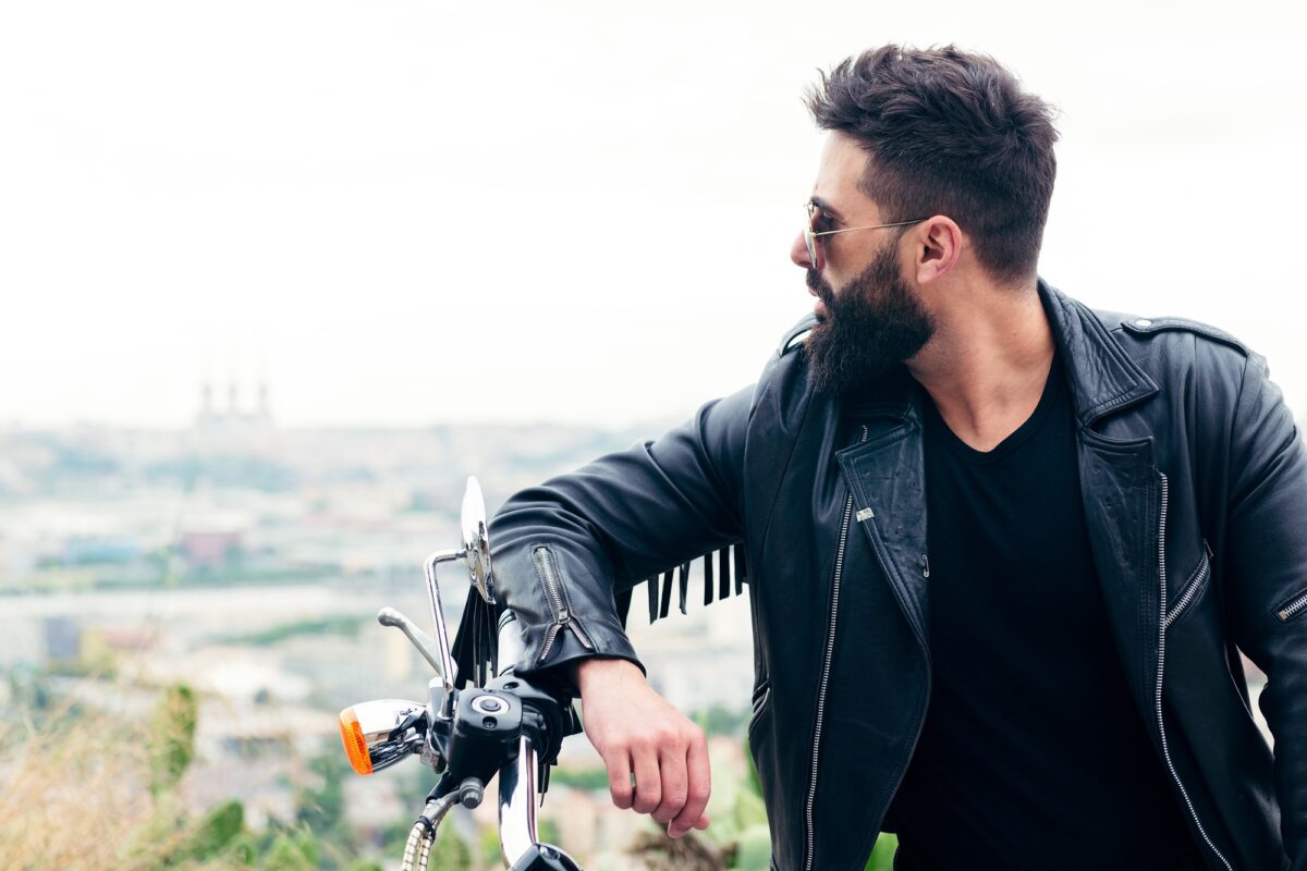 homme en blouson de cuir penché sur sa moto