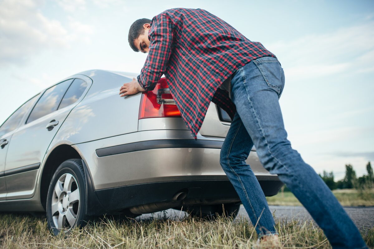 Homme poussant une voiture cassée, vue latérale