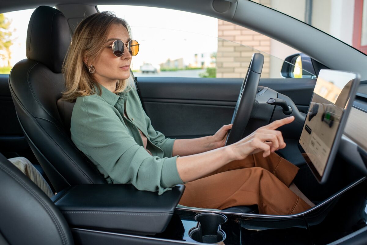 Jeune conductrice pointant du doigt l'écran tout en choisissant son lieu de destination