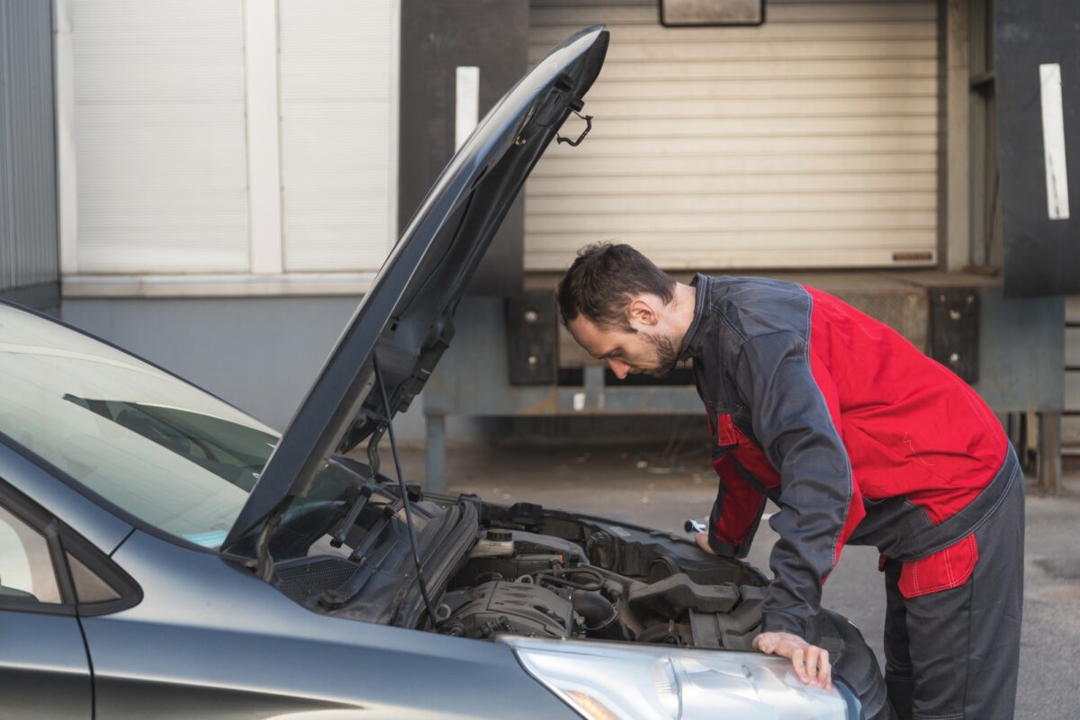Mécanicien automobile examinant la voiture sous le capot lors de l'inspection technique de la voiture