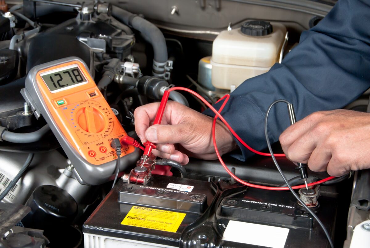 Mécanicien automobile vérifiant la tension de la batterie de la voiture