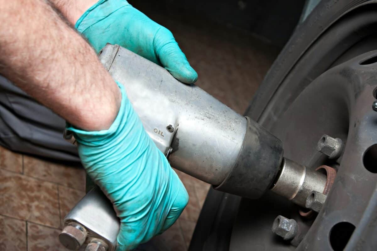 Mechanic changing wheel on car with impact wrench. mechanic man with electric screwdriver.