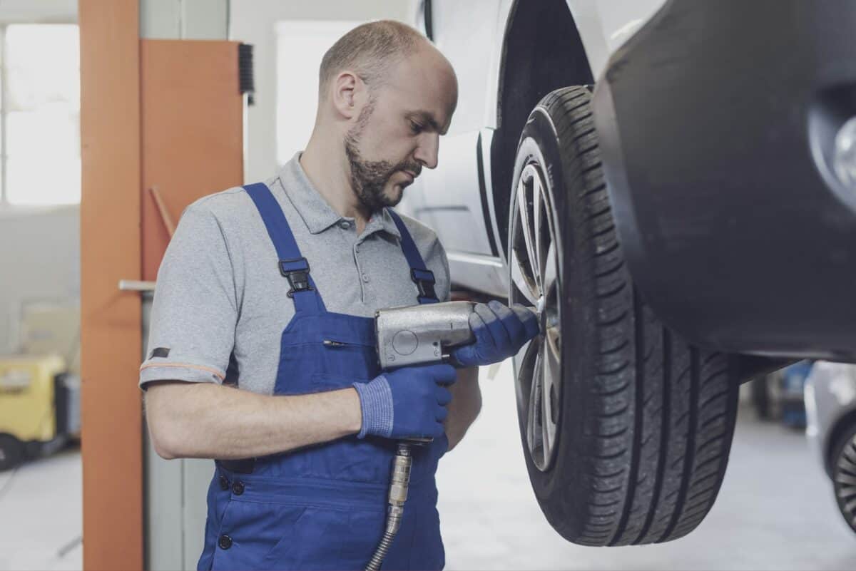 Mechanic doing a wheel replacement using a pneumatic wrench