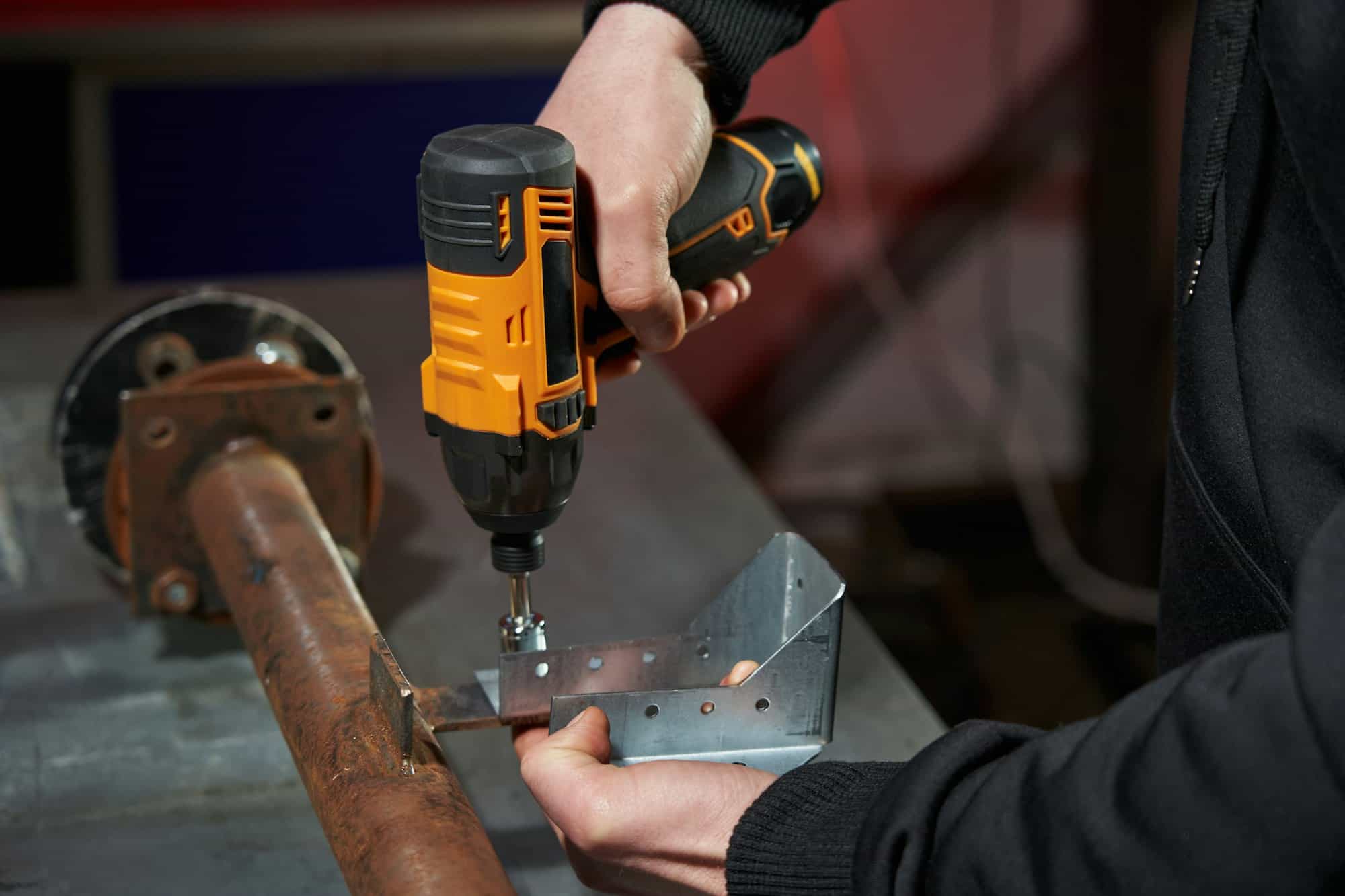 men's hands screw connect two parts with an electric cordless wrench