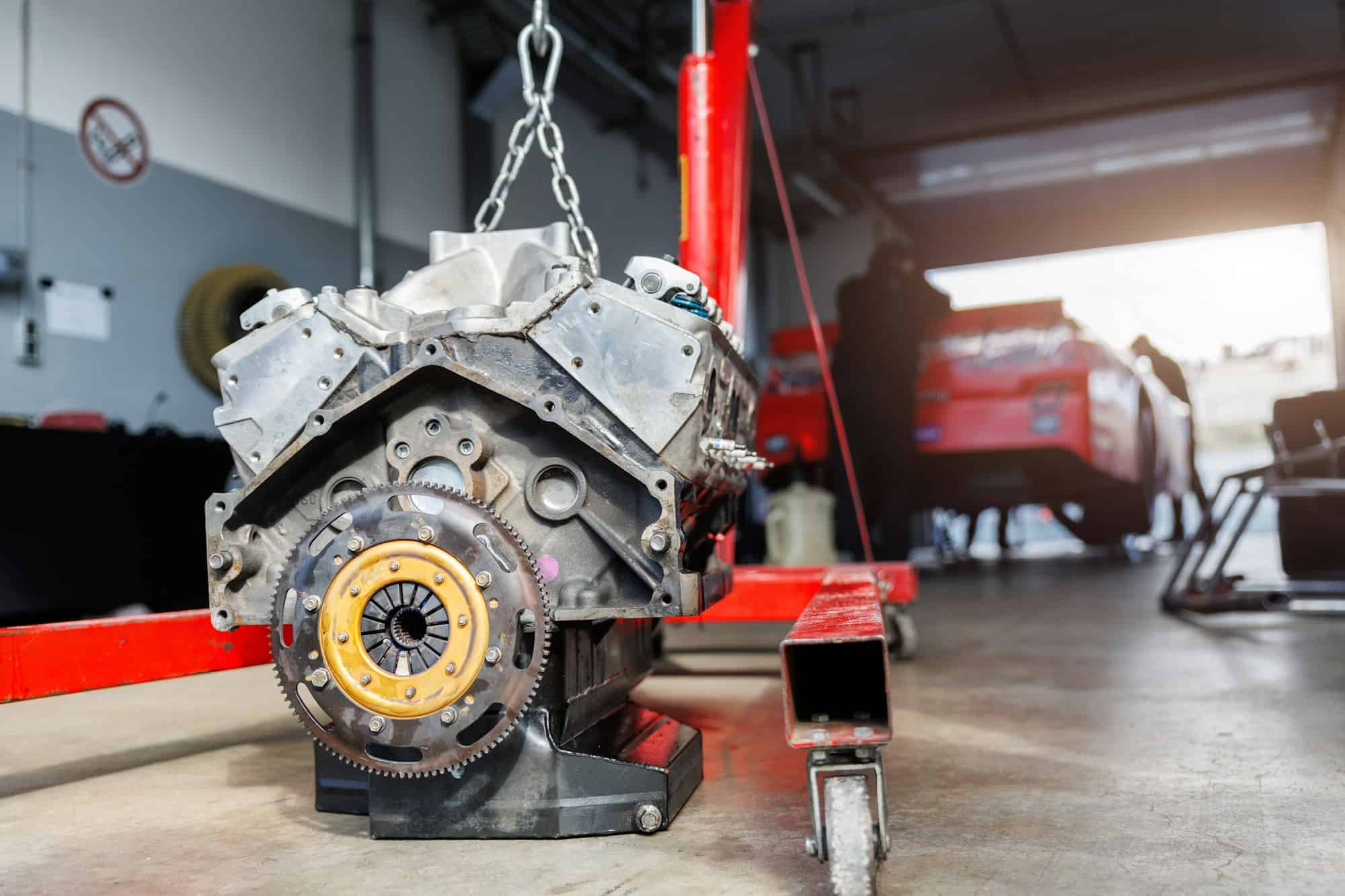 Motorsport pit lane garage box paddock hanged v8 engine suspended crane lift chain hook. Racing