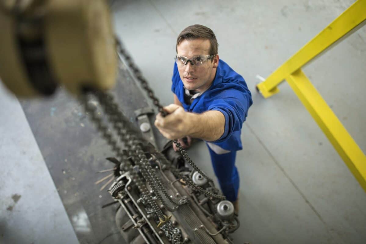 Overhead view of male car mechanic winching car engine in repair garage
