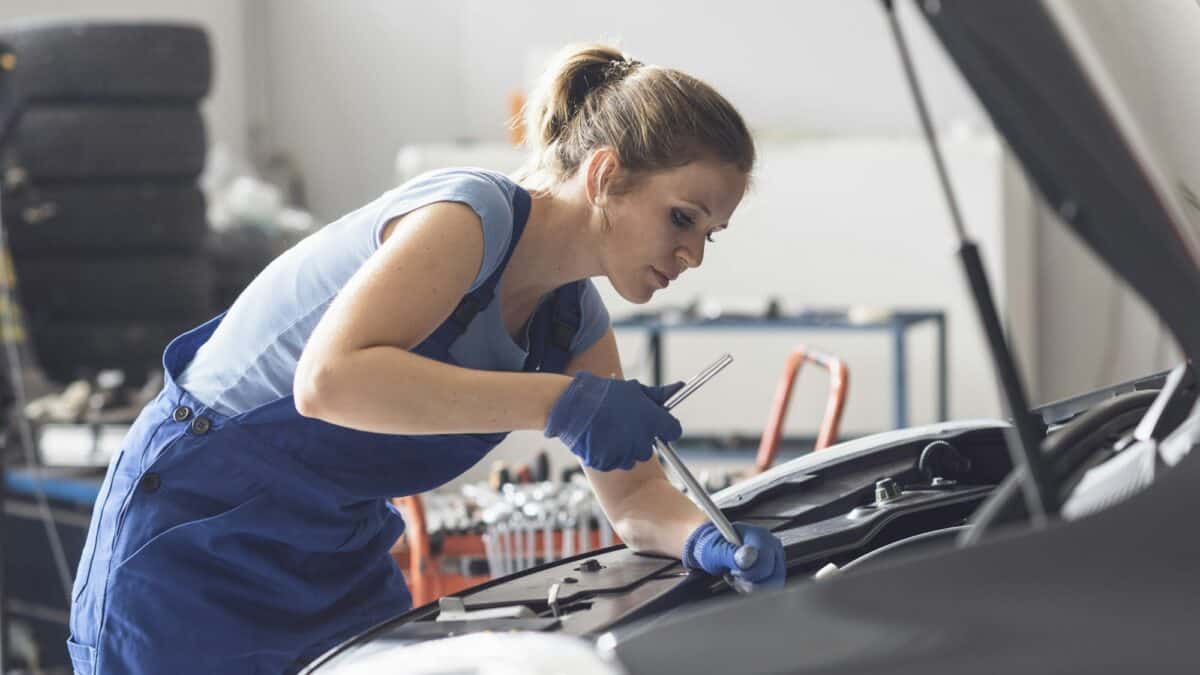 Professional female mechanic fixing a car engine