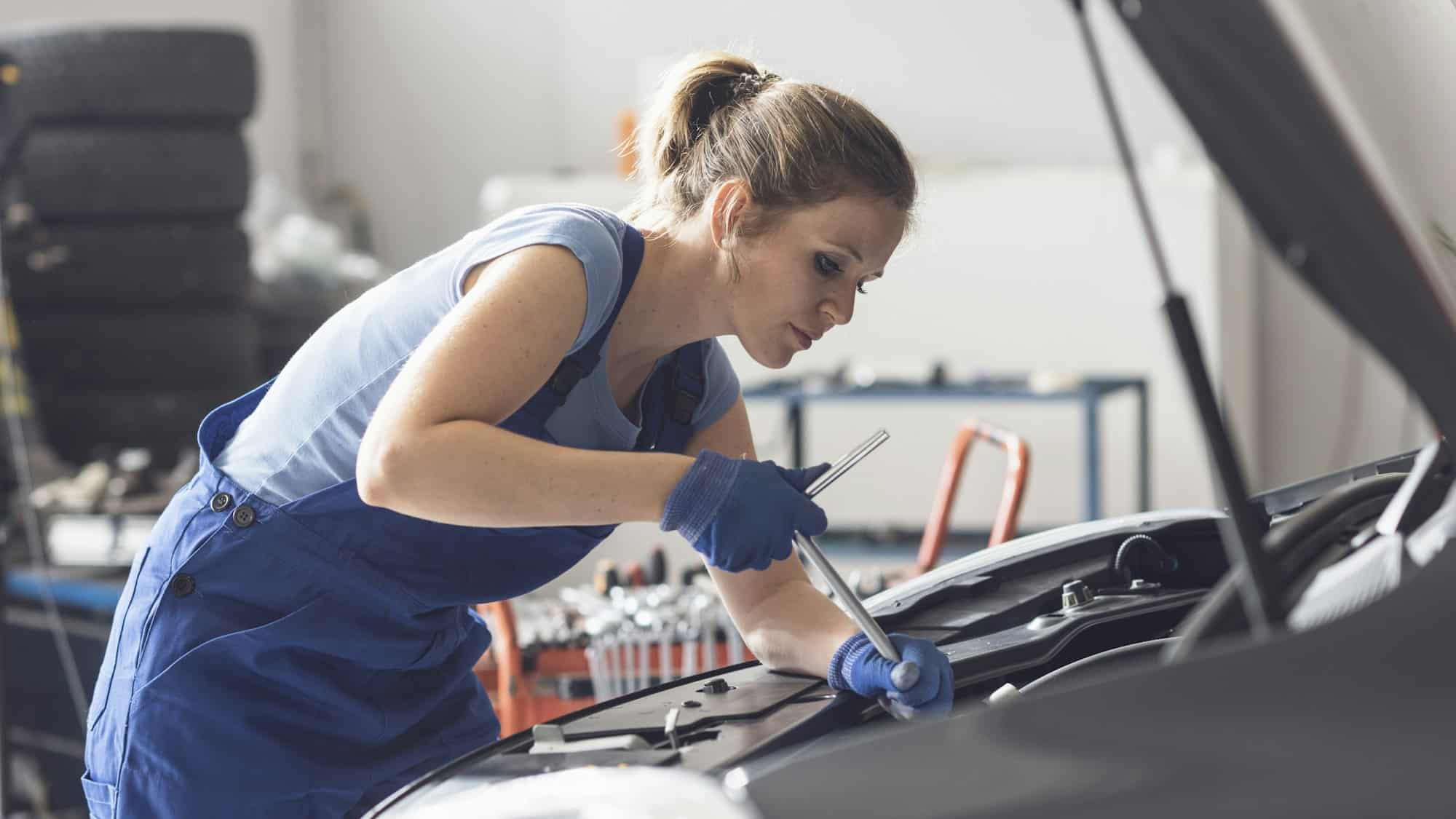 Professional female mechanic fixing a car engine