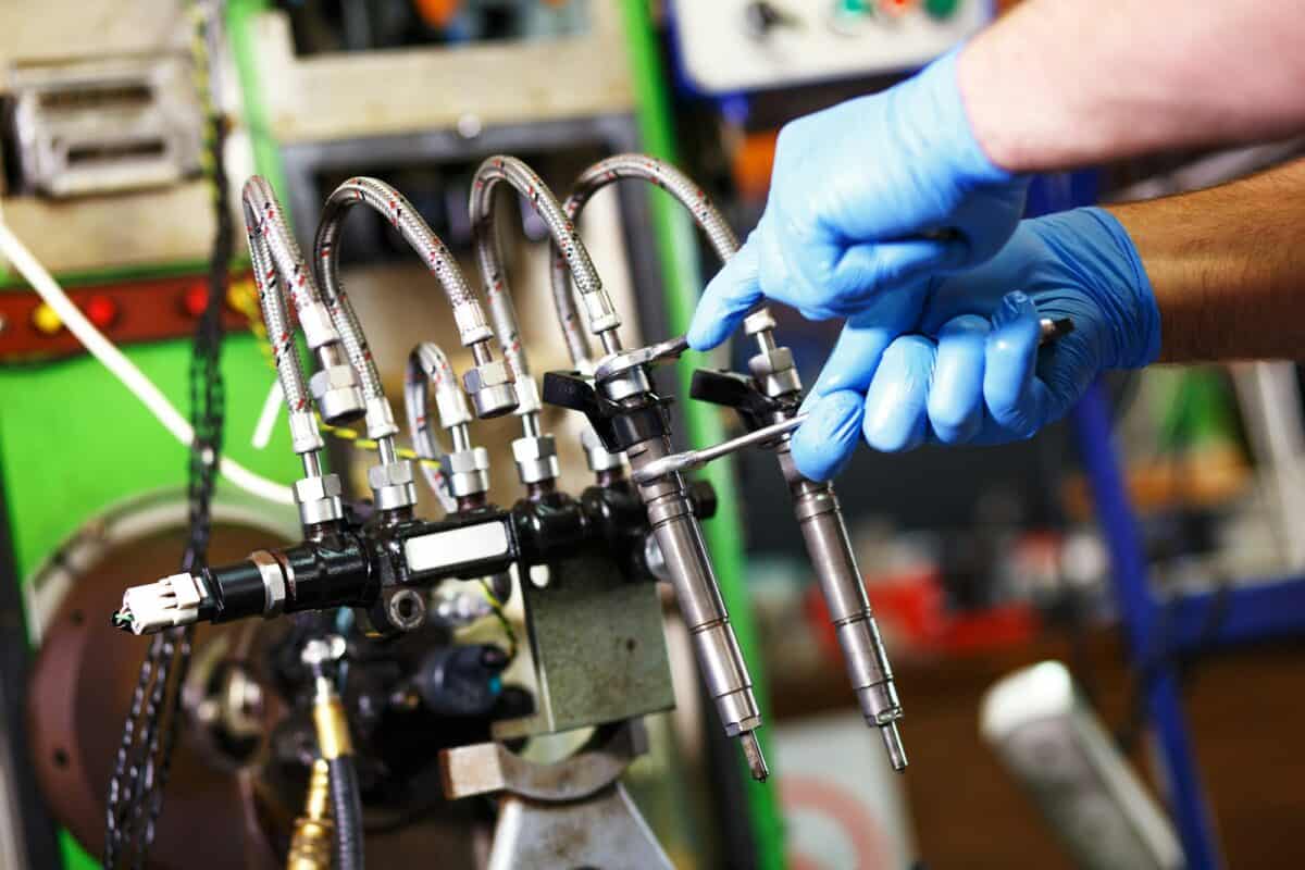 Professional mechanic testing diesel injector in his workshop.