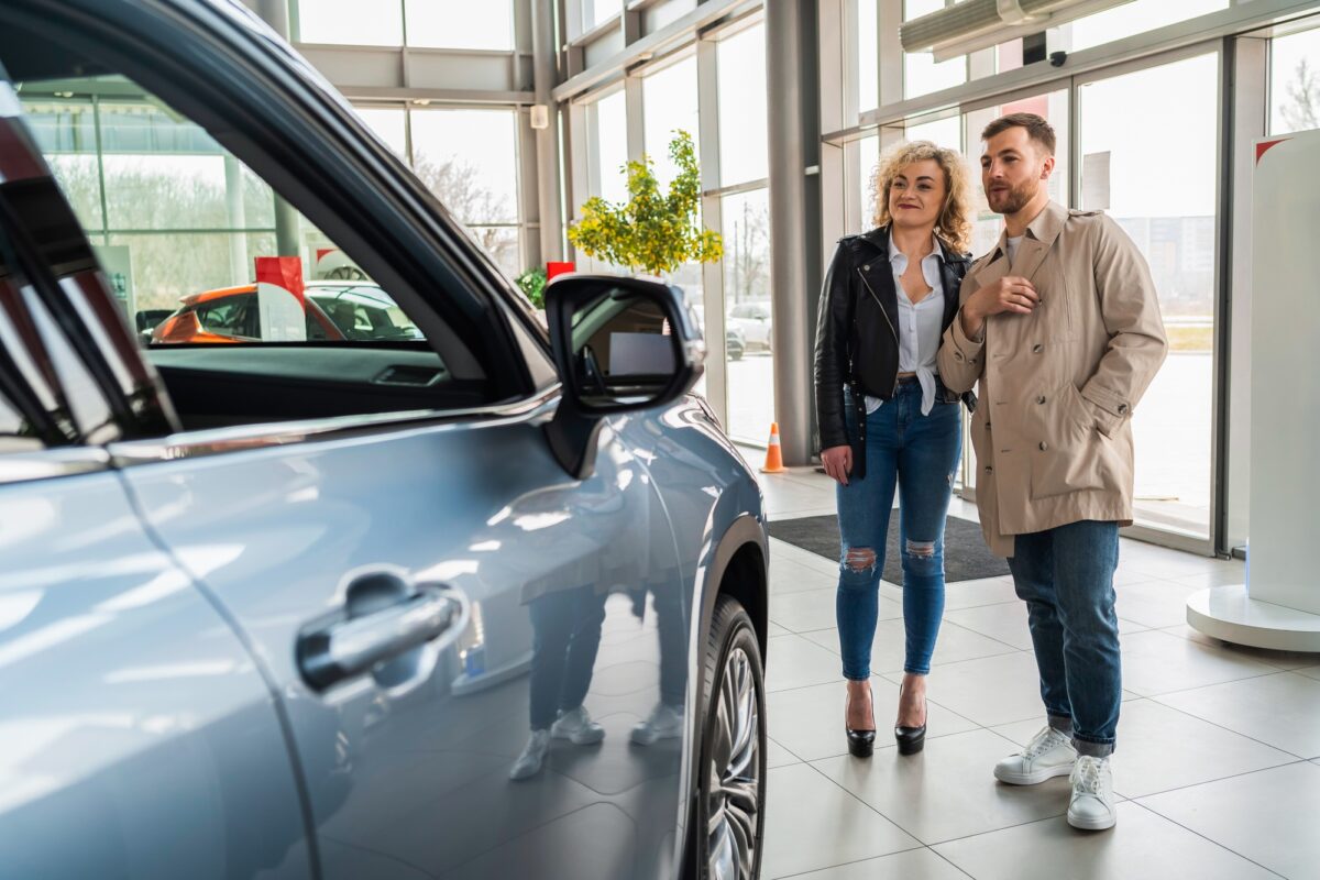 Un beau couple chez un concessionnaire automobile choisit une voiture