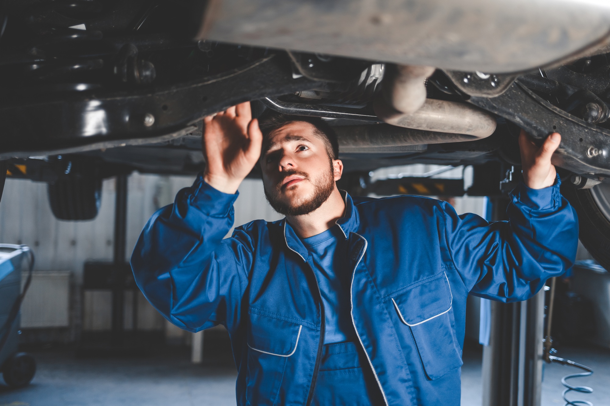 Un mécanicien automobile inspecte la suspension d'une voiture. Diagnostic de l'état de la voiture