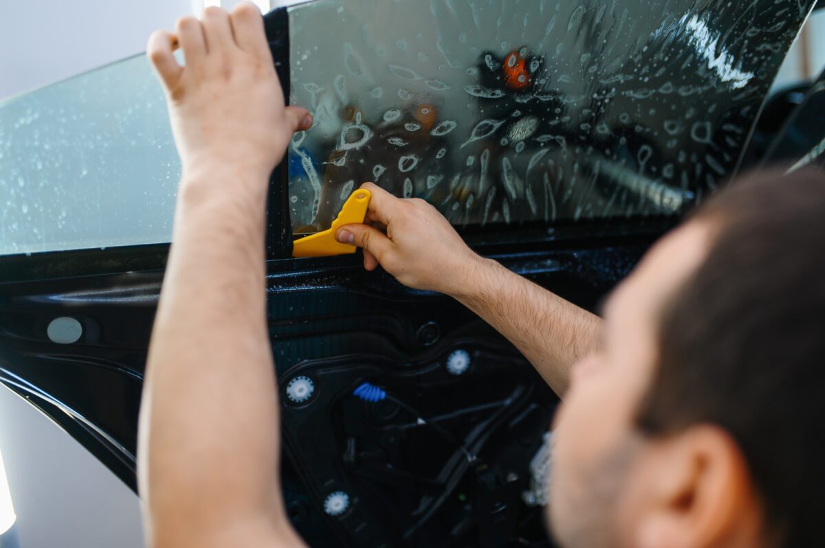 Un travailleur installe un système de teinture pour voiture, un service de tuning