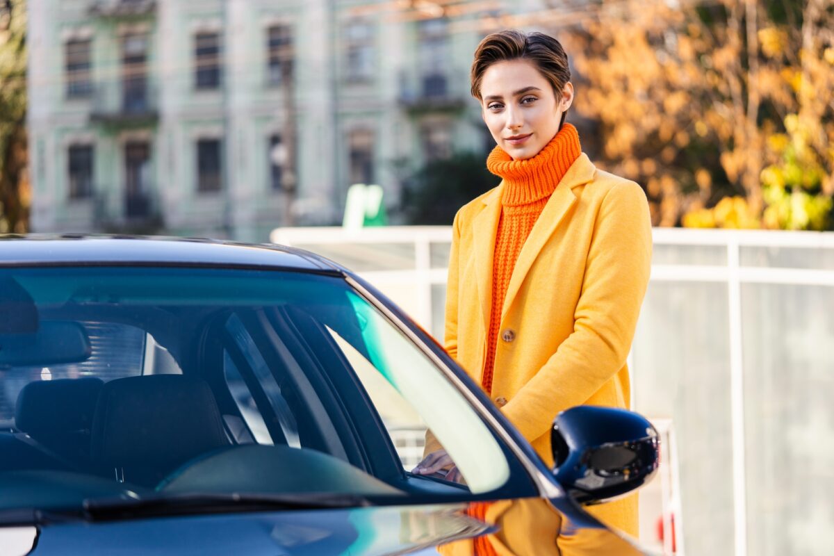 Une belle jeune femme aux cheveux courts conduit une voiture en ville