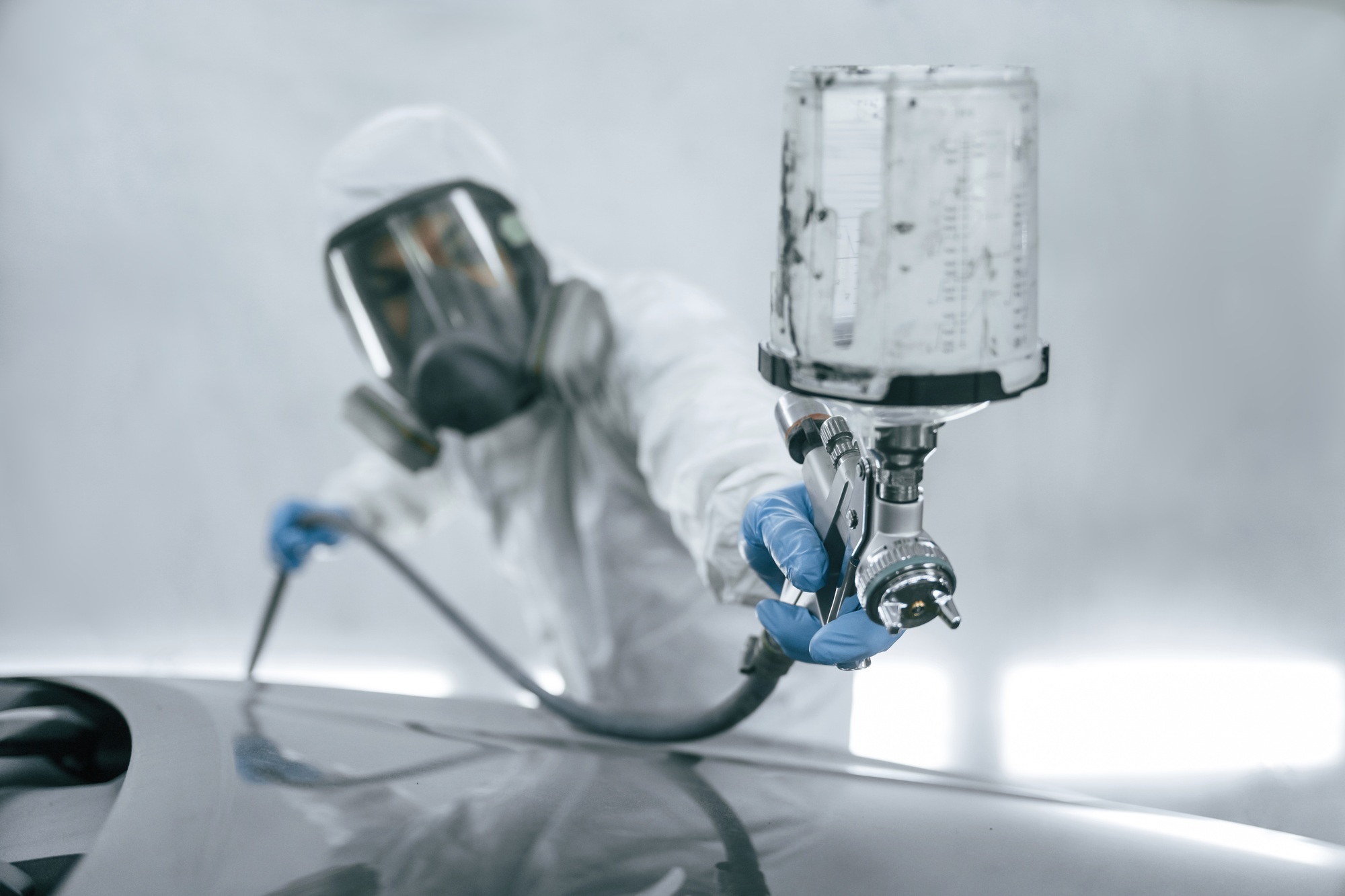 Vue rapprochée d'un homme qui peint une voiture à l'aide d'un spray.